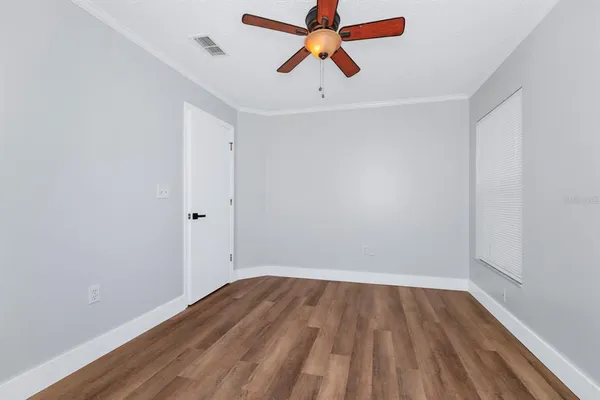 an empty room with wooden floor and ceiling fan