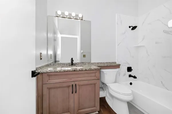 a bathroom with a granite countertop toilet a sink and a mirror