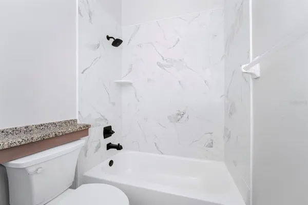 a bathroom with a granite countertop bathtub shower and toilet