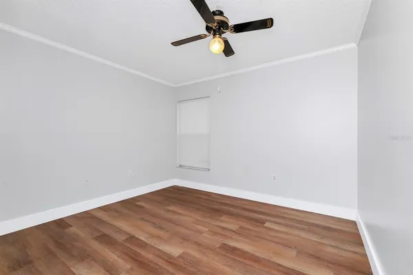 an empty room with wooden floor and a ceiling fan