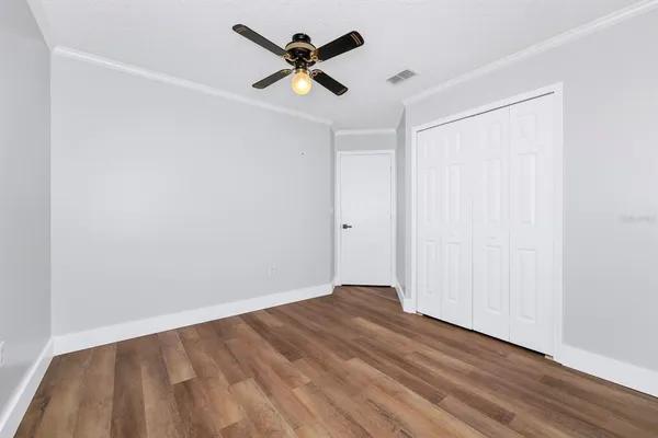 an empty room with wooden floor and ceiling fan