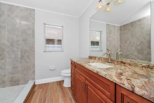 a bathroom with a granite countertop sink a toilet and shower