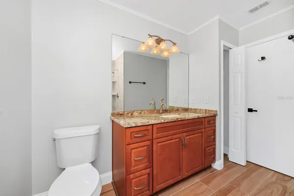 a bathroom with a granite countertop toilet sink and mirror