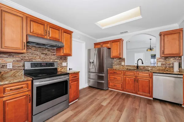 a kitchen with stainless steel appliances granite countertop a stove cabinets and a wooden floor