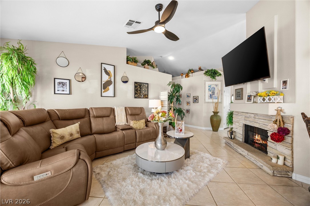 814 Manor Shores Road Henderson, NV 89002 - Photo 14 of 40 A stone fireplace anchors this living space beneath high ceilings and tile flooring.