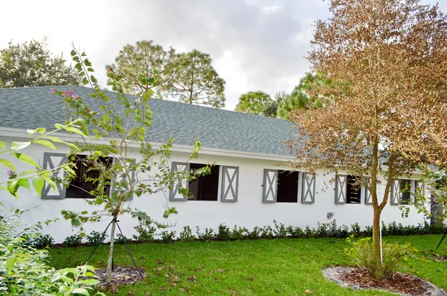 a view of a house with a big yard and large trees