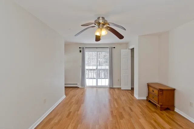 a view of empty room with wooden floor and fan