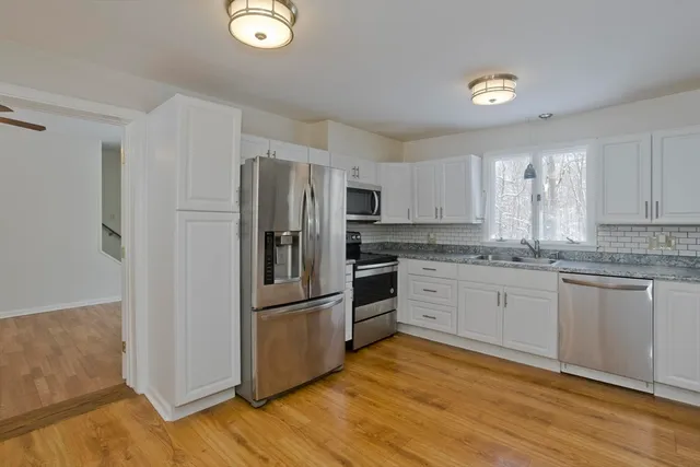 a kitchen with granite countertop a refrigerator cabinets and wooden floor