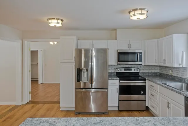 a kitchen with a refrigerator stainless steel appliances wooden floor and dining table