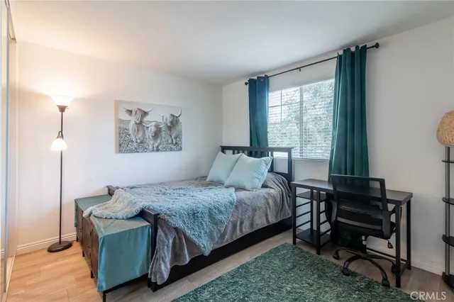 a bedroom with a bed wooden floor and window