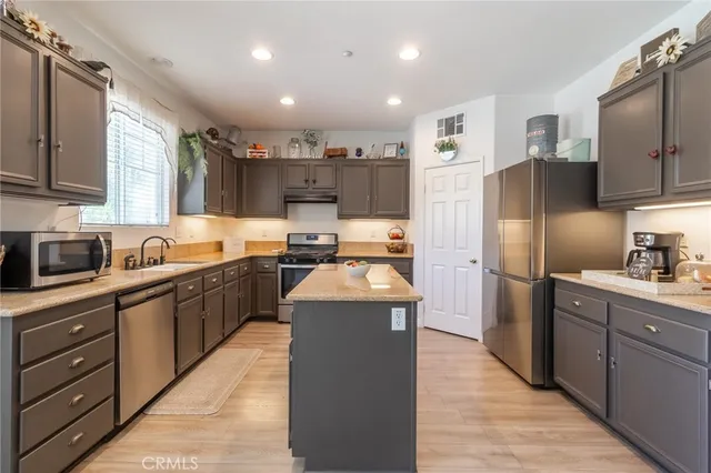 a kitchen with stainless steel appliances granite countertop a refrigerator a sink and a stove