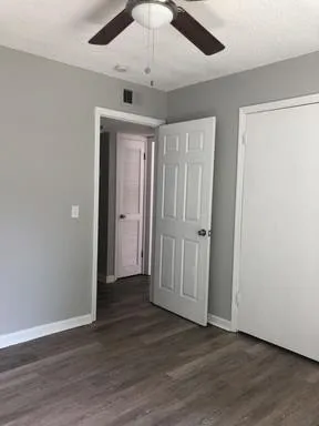 an empty room with wooden floor ceiling fan and windows