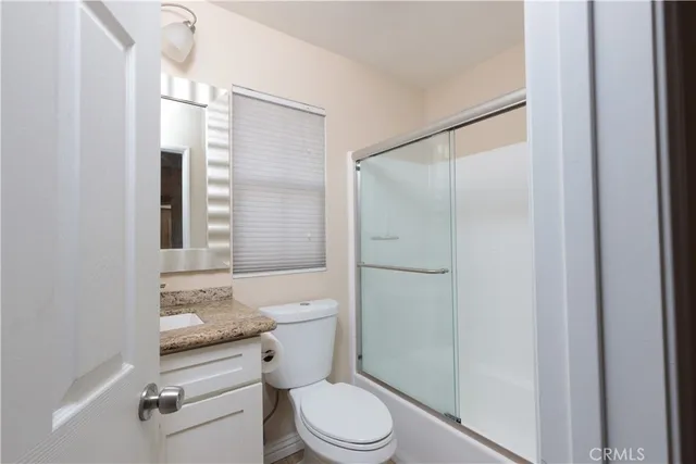 a bathroom with a granite countertop toilet a sink and a mirror