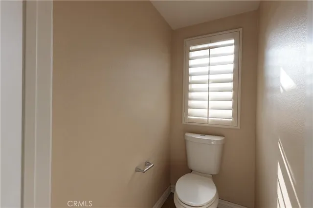 a white toilet sitting in a bathroom next to a window
