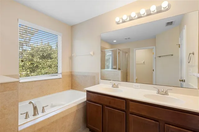 a bathroom with a tub double sink and mirror