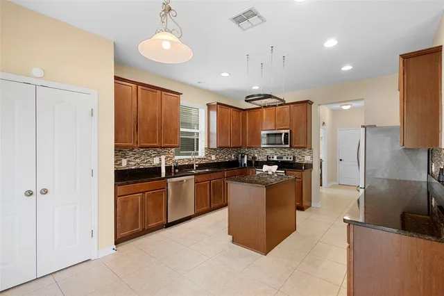 a kitchen with stainless steel appliances granite countertop a refrigerator a sink a stove and oven with wooden floor
