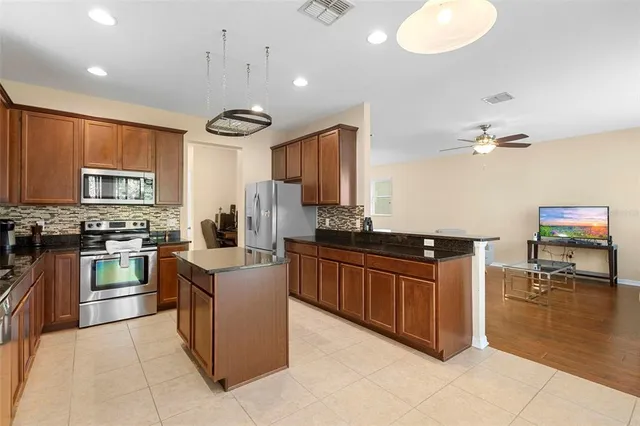 a kitchen with stainless steel appliances granite countertop a stove top oven a sink dishwasher and a refrigerator