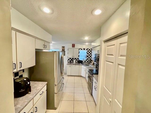30 San Rafael Court Palm Coast, FL 32137 - Photo 24 of 32 a kitchen with a refrigerator and white cabinets