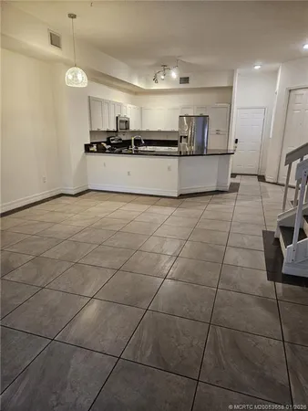 a large kitchen with granite countertop a stove a sink a counter space and cabinets
