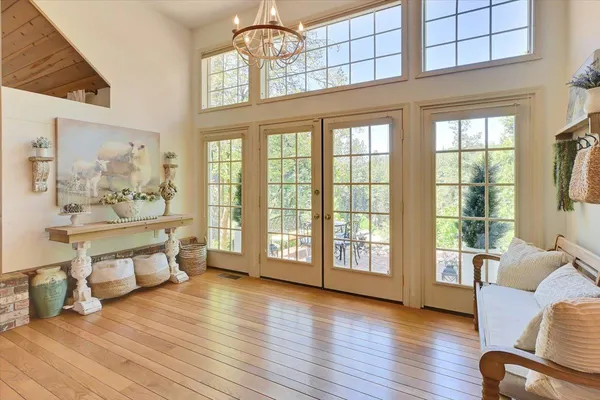 a living room with furniture a chandelier and a dining table with wooden floor