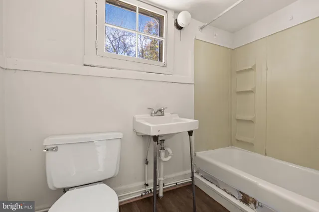 a view of an empty room with wooden floor and windows