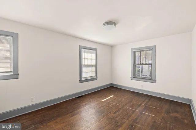 an empty room with wooden floor and natural light