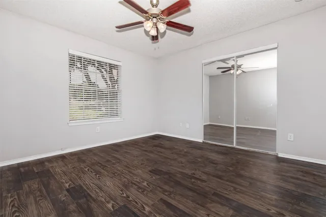 a view of an empty room with a window and wooden floor