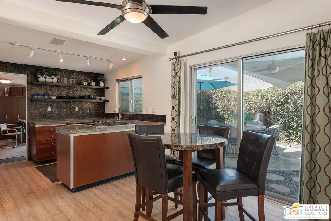 a kitchen with stainless steel appliances granite countertop a table chairs sink and wooden floor