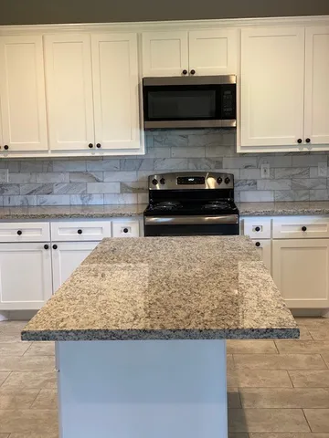 a kitchen with granite countertop a sink a stove and a microwave