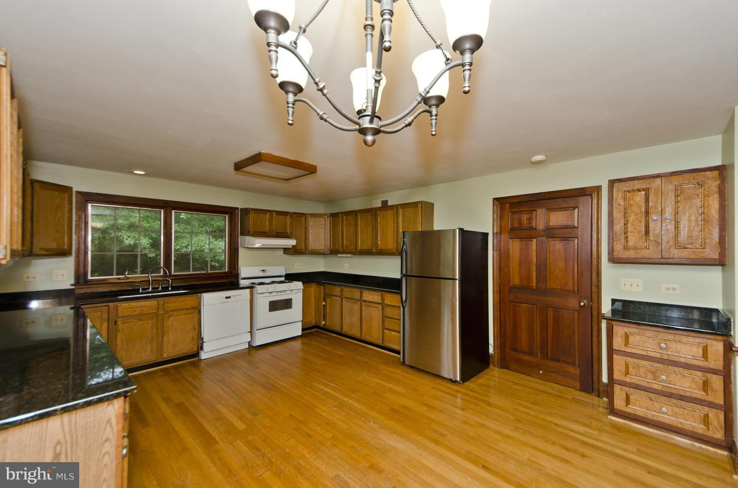 7120 Georgetown Pike McLean, VA 22101 - Photo 9 of 30 a kitchen with stainless steel appliances granite countertop a refrigerator a sink dishwasher a stove and a dining table with wooden floor