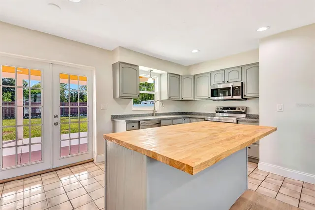 a kitchen with stainless steel appliances granite countertop a refrigerator a sink a stove top oven and a counter space