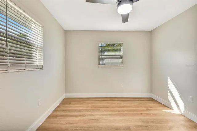 a view of empty room with wooden floor and fan