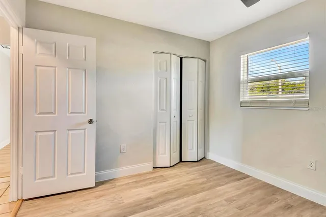 an empty room with wooden floor and closet area