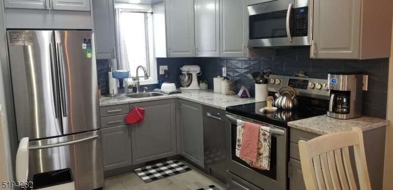 a kitchen with stainless steel appliances granite countertop a refrigerator a stove a sink and a microwave