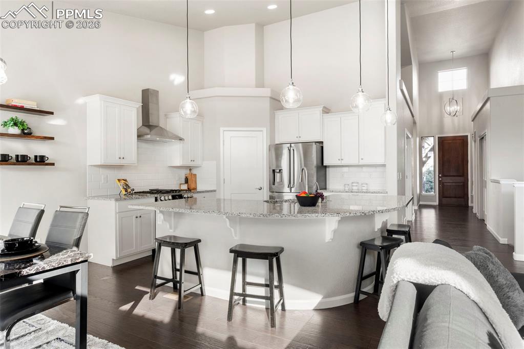 1073 Native Dancer Terrace Colorado Springs, CO 80921 - Photo 15 of 48 Kitchen featuring a high ceiling, dark wood finished floors, white cabinetry, stainless steel appliances, and a spacious island