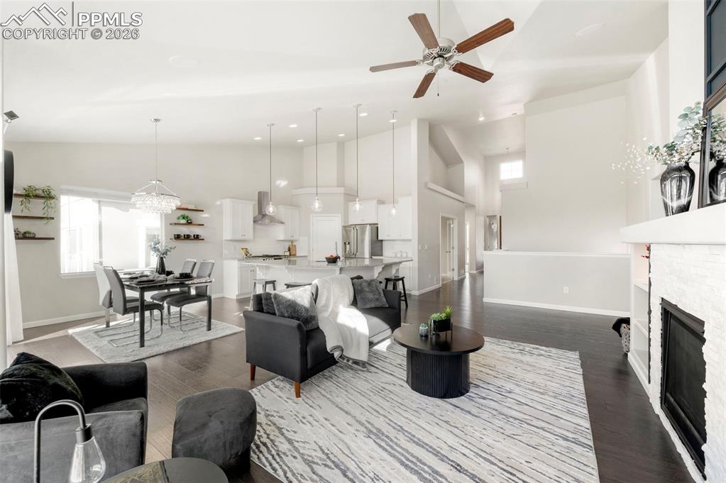 1073 Native Dancer Terrace Colorado Springs, CO 80921 - Photo 16 of 48 Living area featuring a fireplace, a ceiling fan, dark wood finished floors, vaulted ceiling, and suspended lighting
