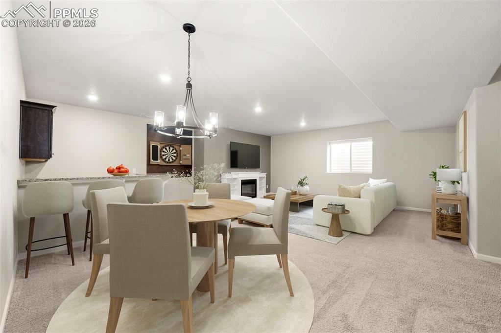 1073 Native Dancer Terrace Colorado Springs, CO 80921 - Photo 33 of 48 Dining room featuring light carpet, a glass covered fireplace, and hanging lights