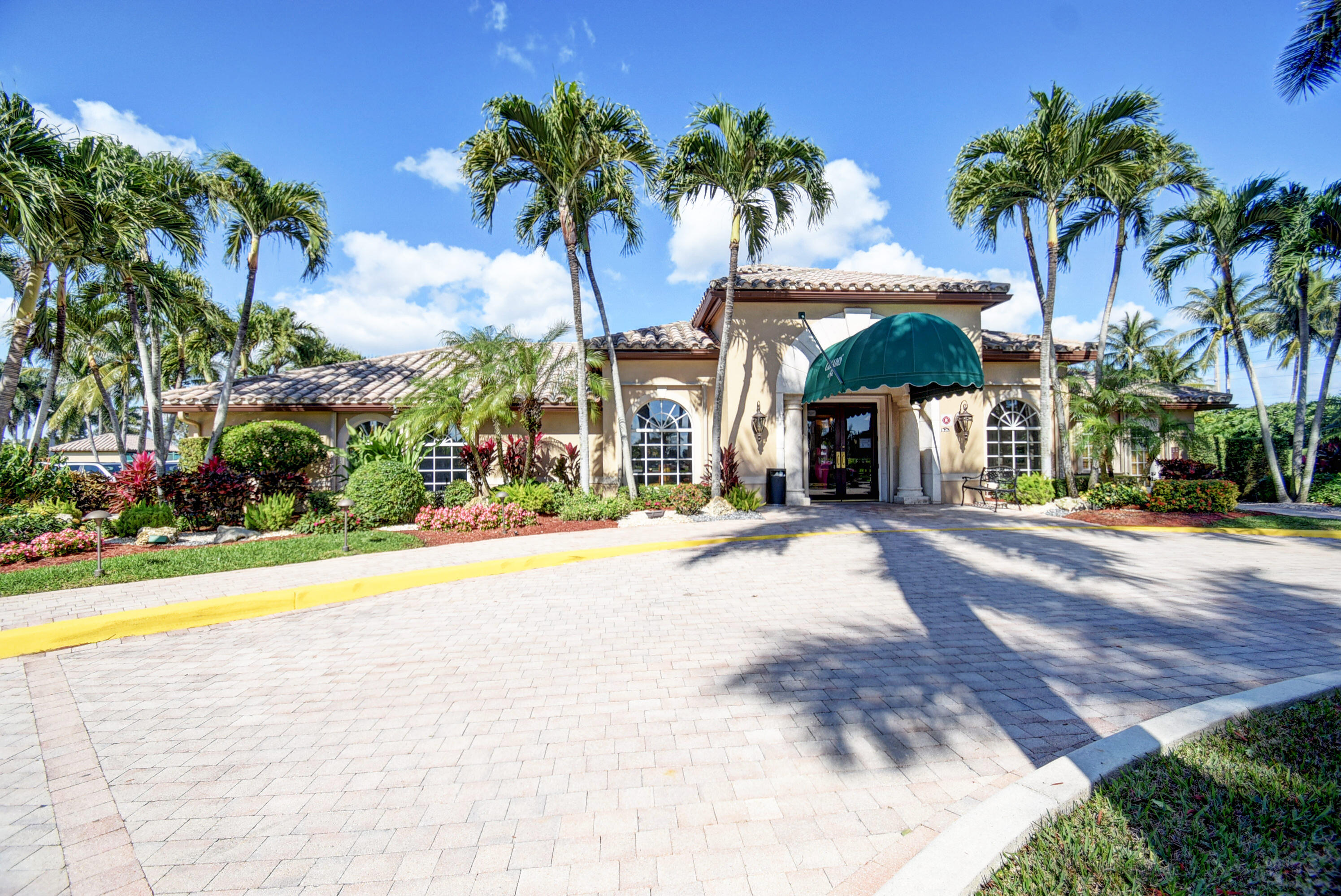 7097 Haviland Circle Boynton Beach, FL 33437 - Photo 63 of 72 a view of a swimming pool with a lawn chairs under palm trees
