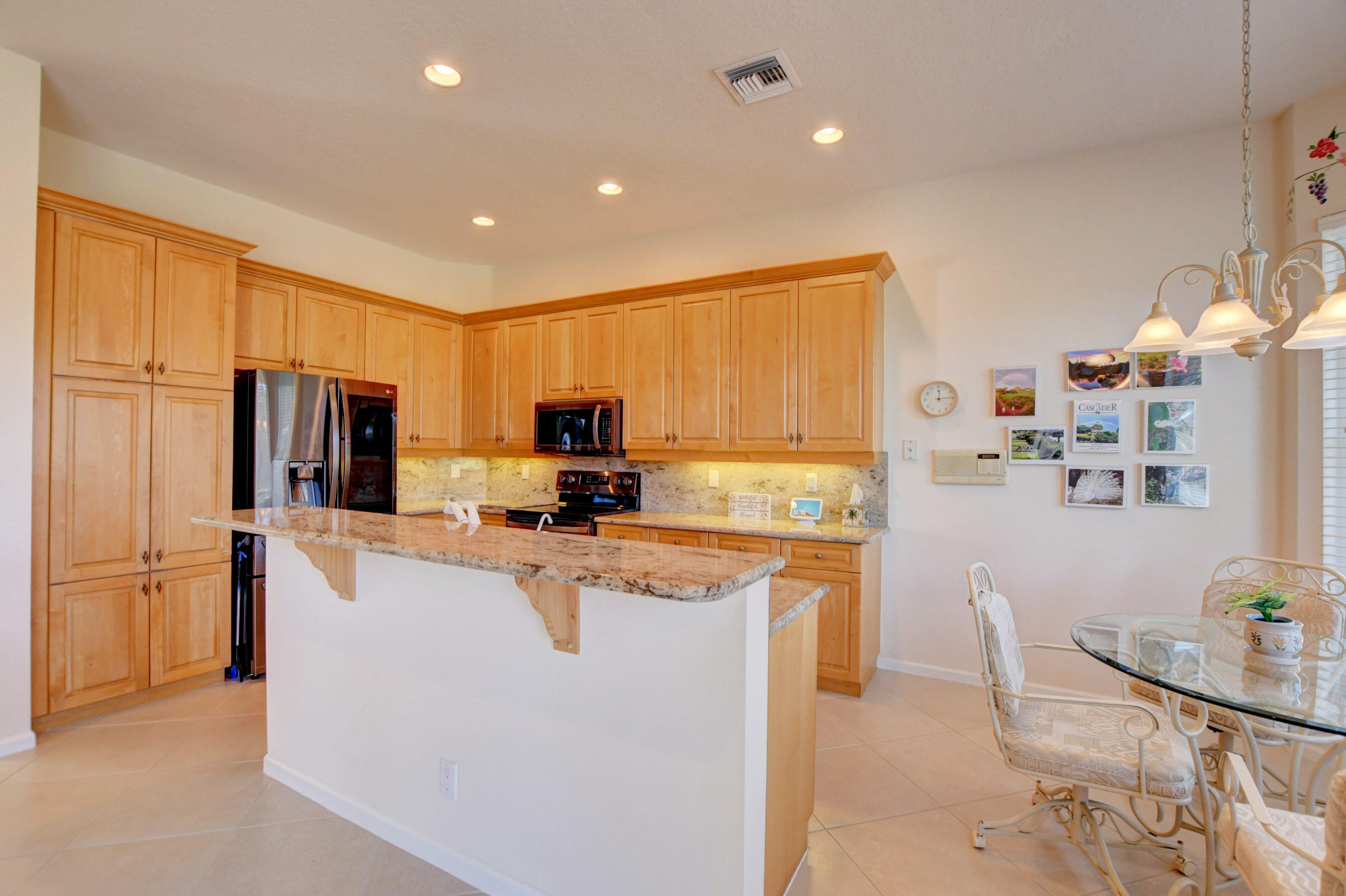 7097 Haviland Circle Boynton Beach, FL 33437 - Photo 10 of 72 a kitchen with stainless steel appliances a refrigerator a sink a stove a dining table and chairs