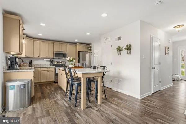 a kitchen with kitchen island wooden floors white appliances and cabinets