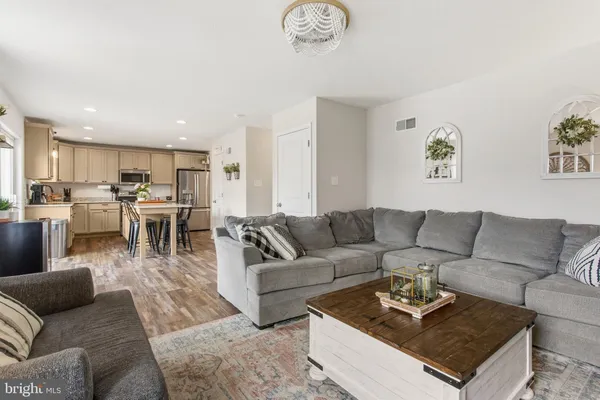 a living room with furniture wooden floor and a kitchen view
