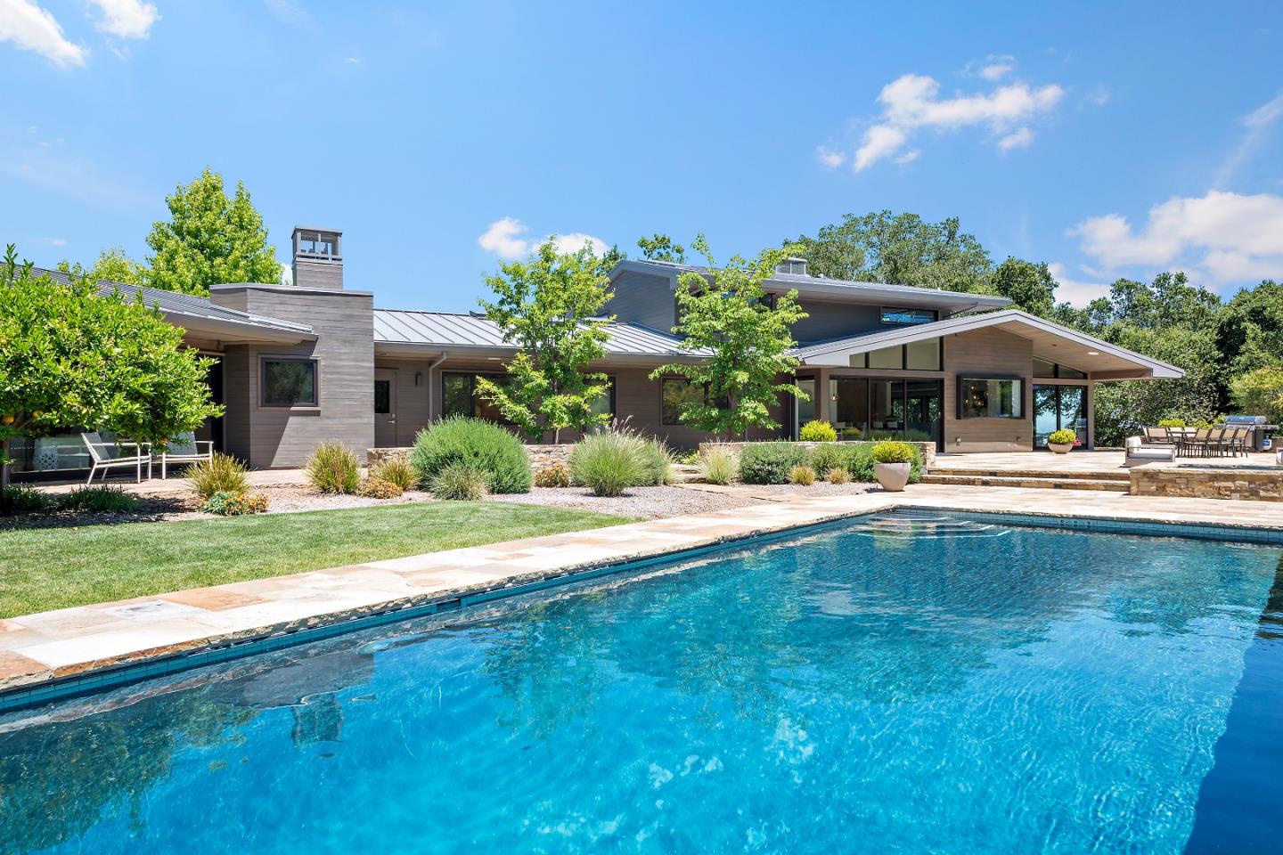 396 Raymundo Drive Woodside, CA 94062 - Photo 31 of 58 a view of a swimming pool with lawn chairs under an umbrella