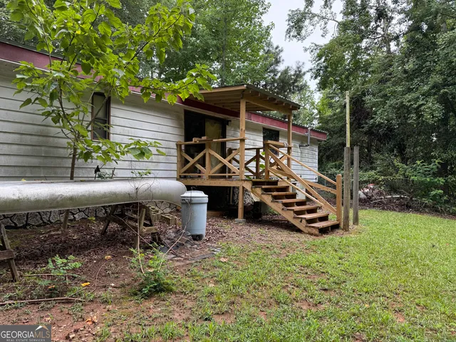 a view of a patio with table and chairs a barbeque with potted plants and large trees