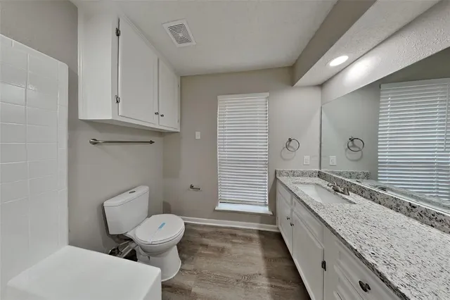 a bathroom with a granite countertop toilet a mirror and a sink