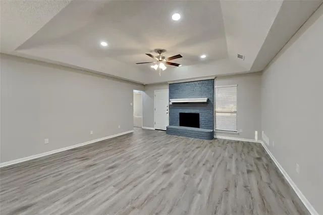 a view of an empty room with a fireplace and a ceiling fan