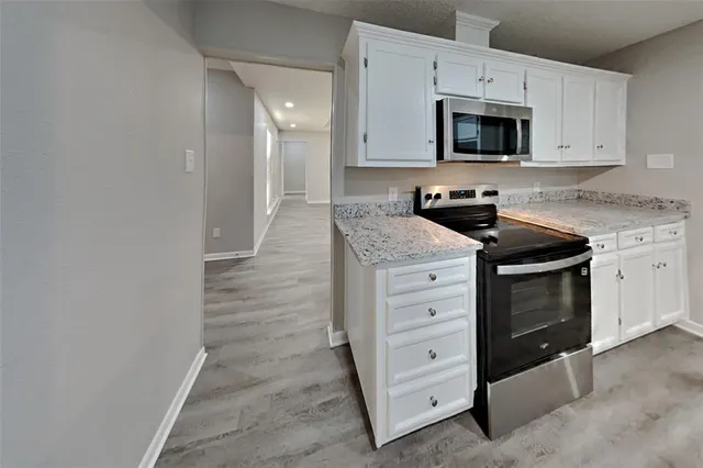 a kitchen with granite countertop white cabinets and stainless steel appliances
