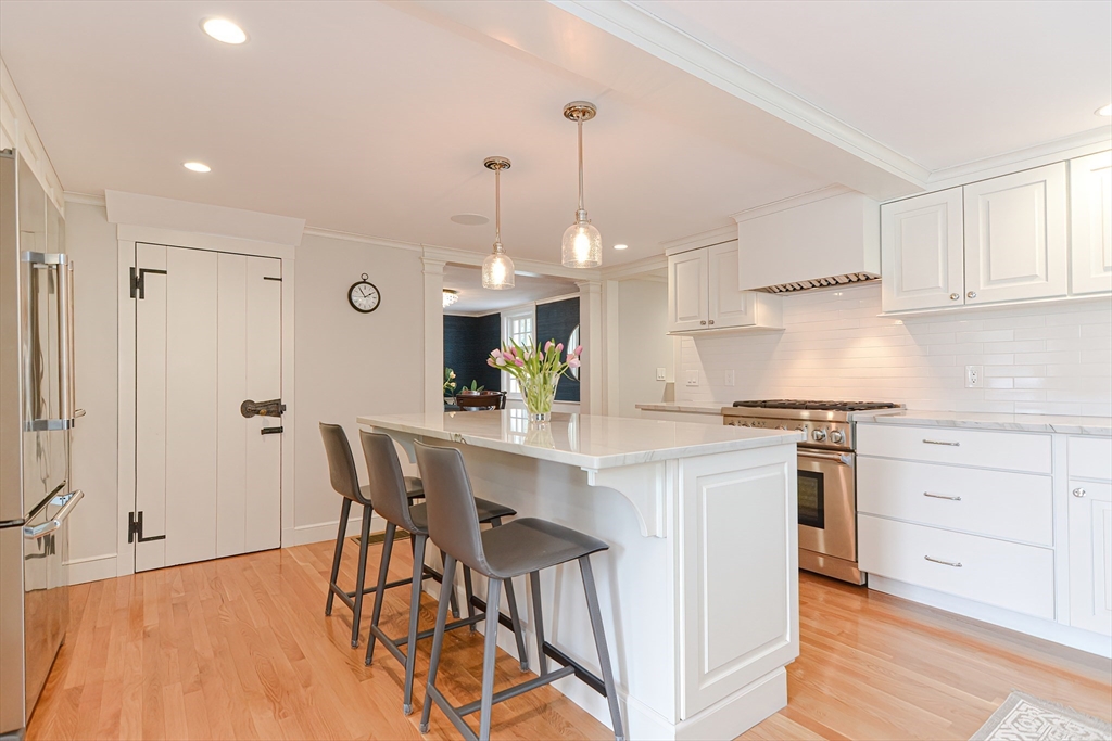 24 Standish Road Wellesley, MA 02481 - Photo 8 of 42 a kitchen with stainless steel appliances kitchen island granite countertop a dining table chairs and white cabinets