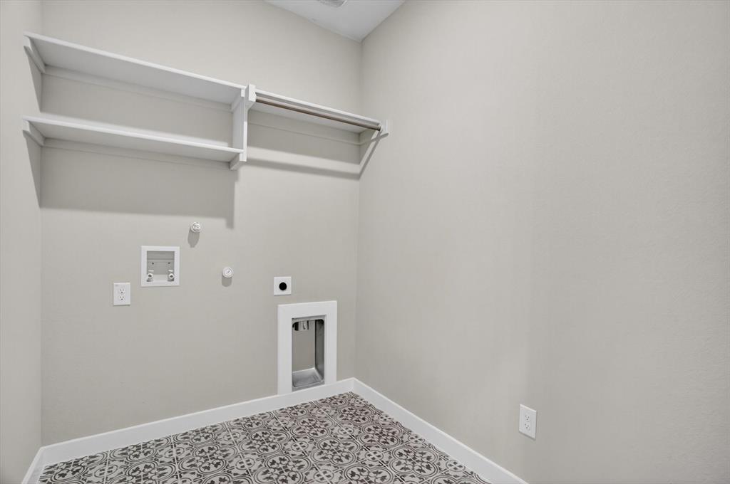 504 Clifton Court Springtown, TX 76082 - Photo 19 of 36 Dedicated laundry area featuring patterned tile flooring, light gray walls, built-in shelving, and a hanging rod