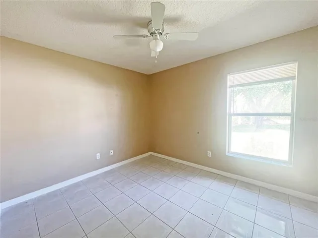 an empty room with windows and ceiling fan