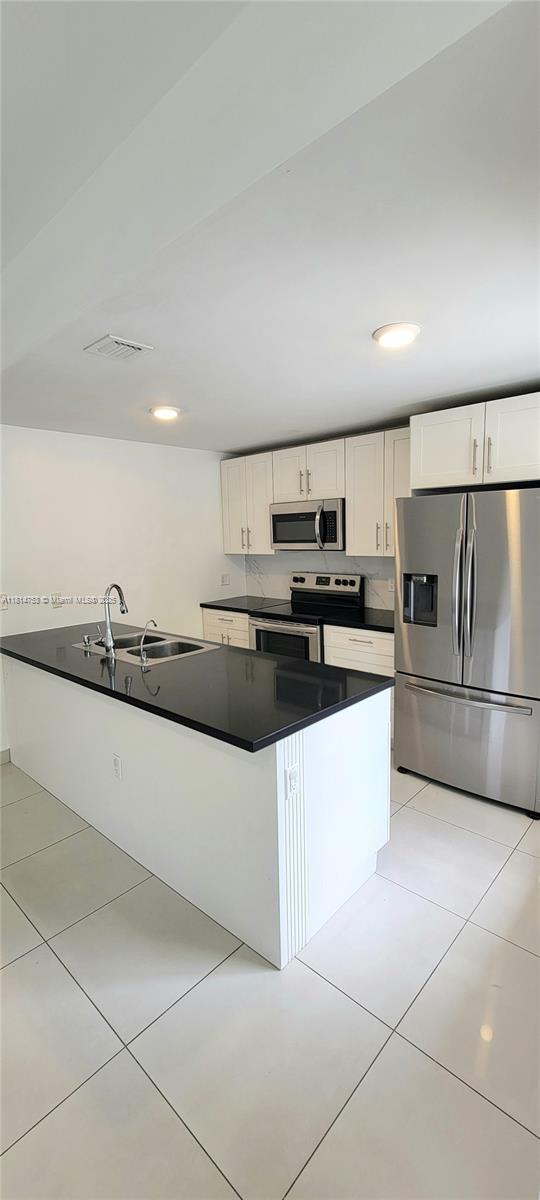 14004 Southwest 259th Street, Unit 14004 Homestead, FL 33032 - Photo 7 of 38 a large kitchen with stainless steel appliances a sink a stove a microwave and cabinets